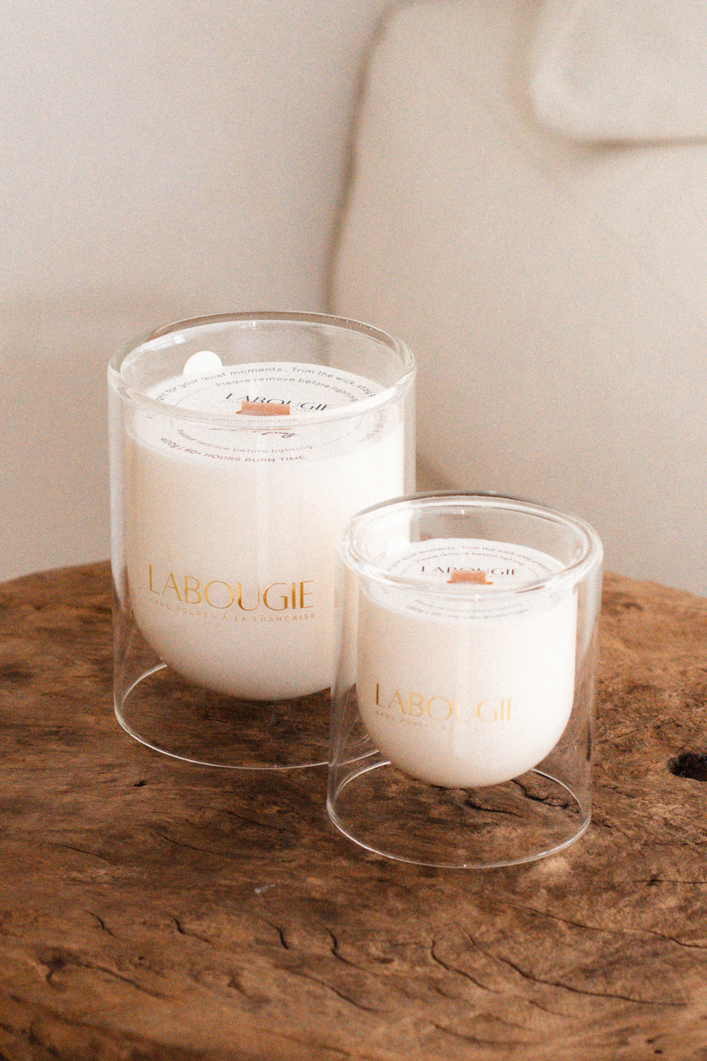 Two white candles in glass holders on a wooden surface with 'Labougie' branding.